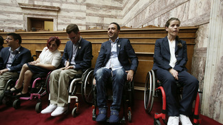Esporte paralímpico grego oferece esperança para refugiados com deficiência Atletas gregos paralímpicos em evento no parlamento do país