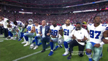 De braços entrelaçados e de joelhos, jogadores de Cowboys e Cardinals protestam durante o hino De braços entrelaçados e de joelhos, jogadores de Cowboys e Cardinals protestam durante o hino